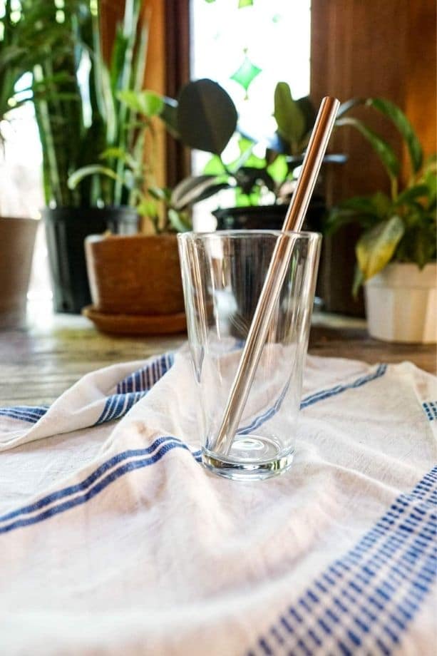 Glass cup with a metal drinking straw in it.