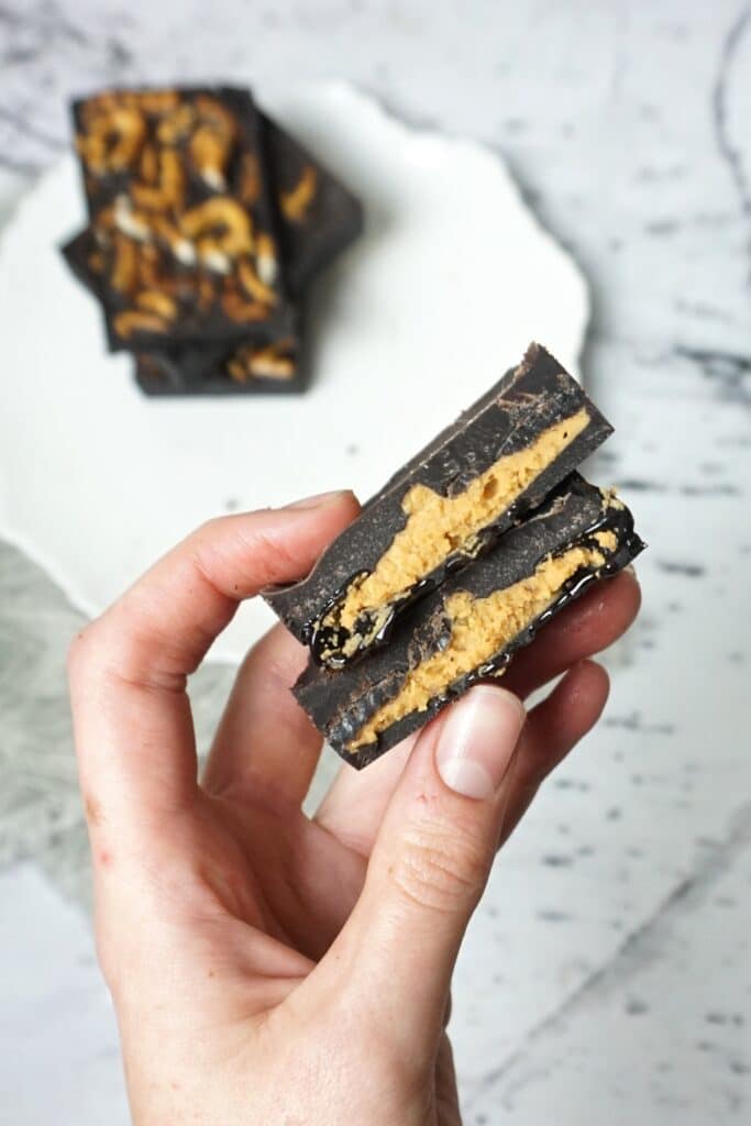 A woman's hand holding chocolate peanut butter pretzel bars